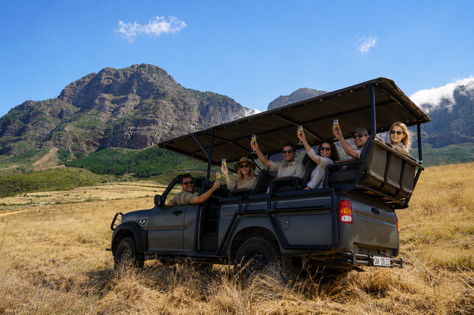 Guests enjoying bubbly aboard the Plaisir Vineyard Safari vehicle with mountain views