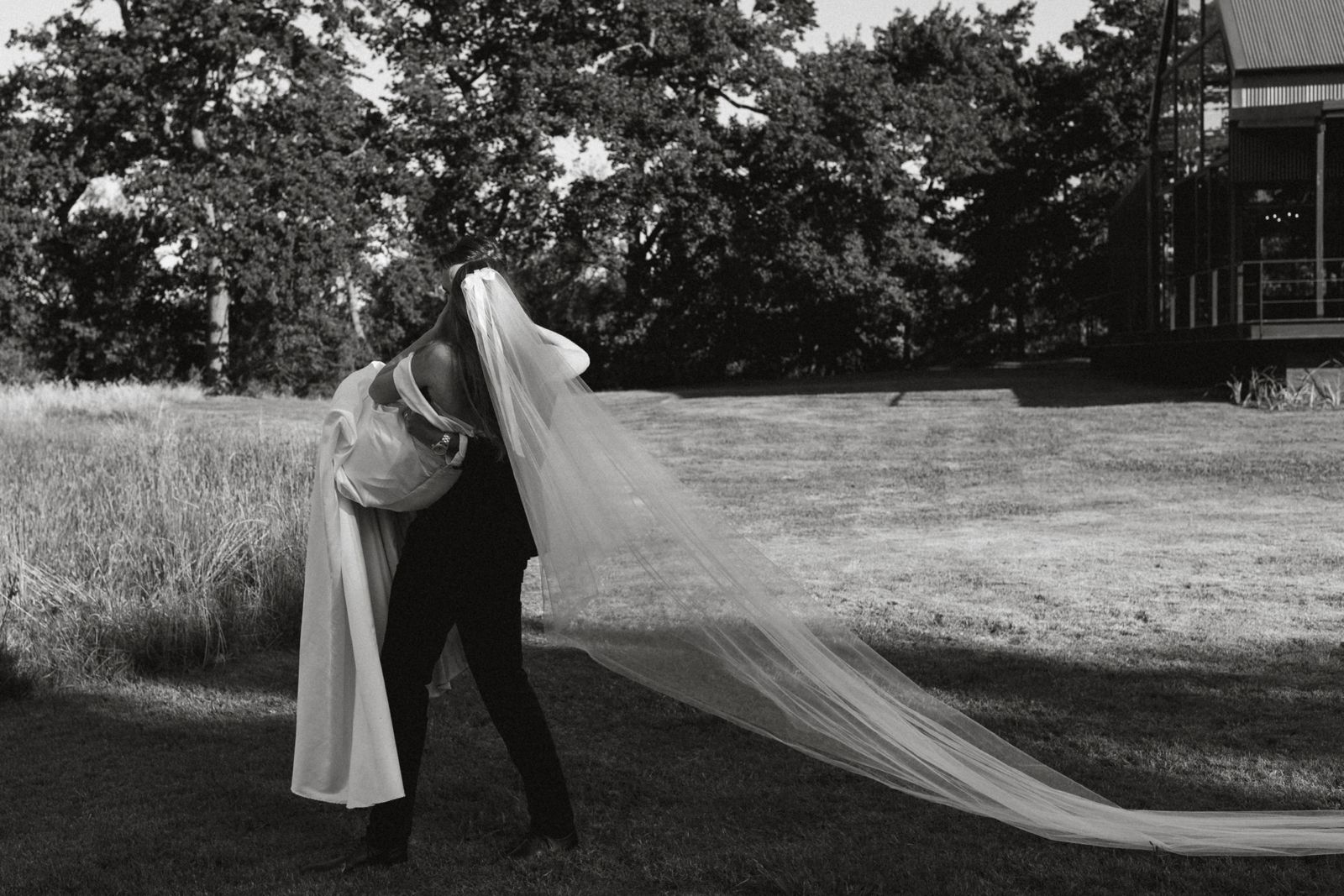 Black and white image of couple embracing with flowing veil