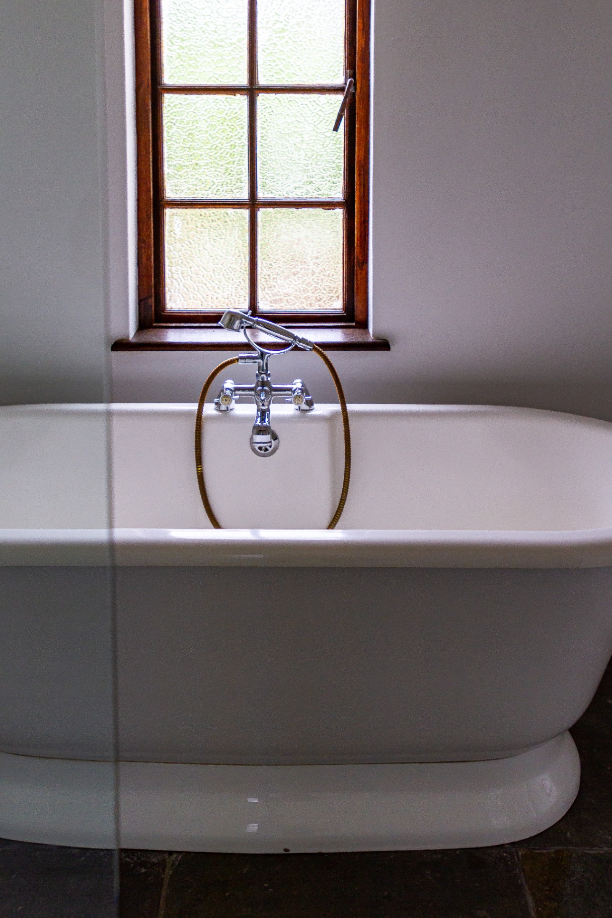 Merle Cottage bathroom with freestanding bath and stained-glass window