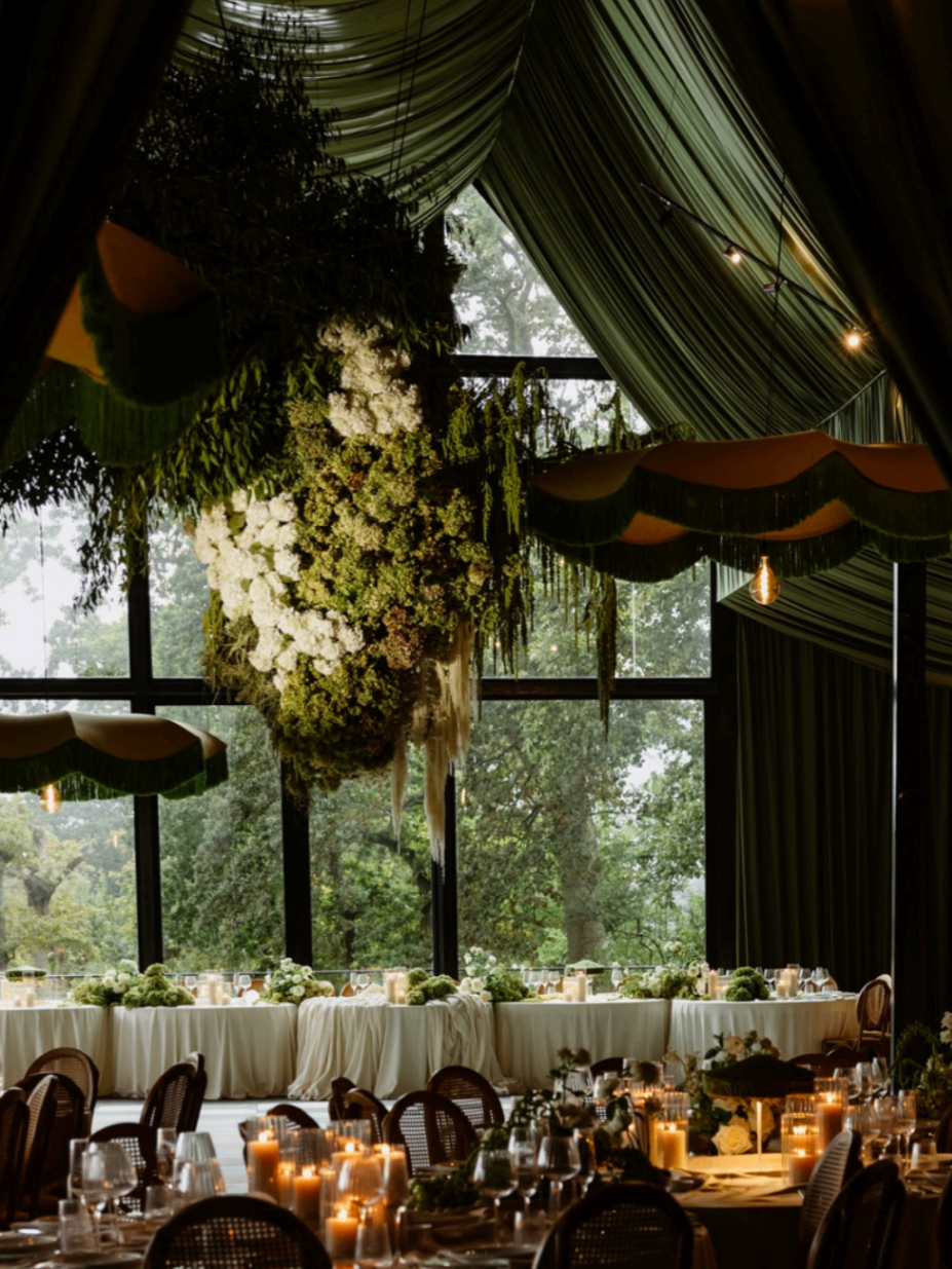 Moody reception venue with dramatic draped ceiling and candlelit tables