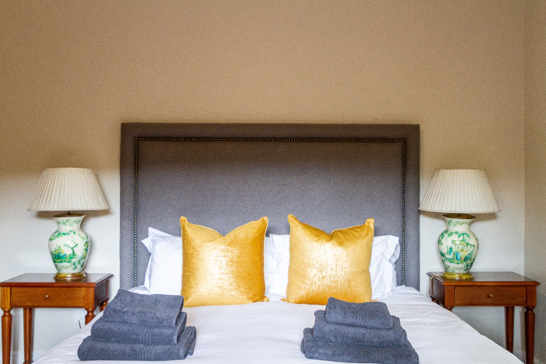 Forest Cottage king bedroom with grey velvet headboard and gold cushions