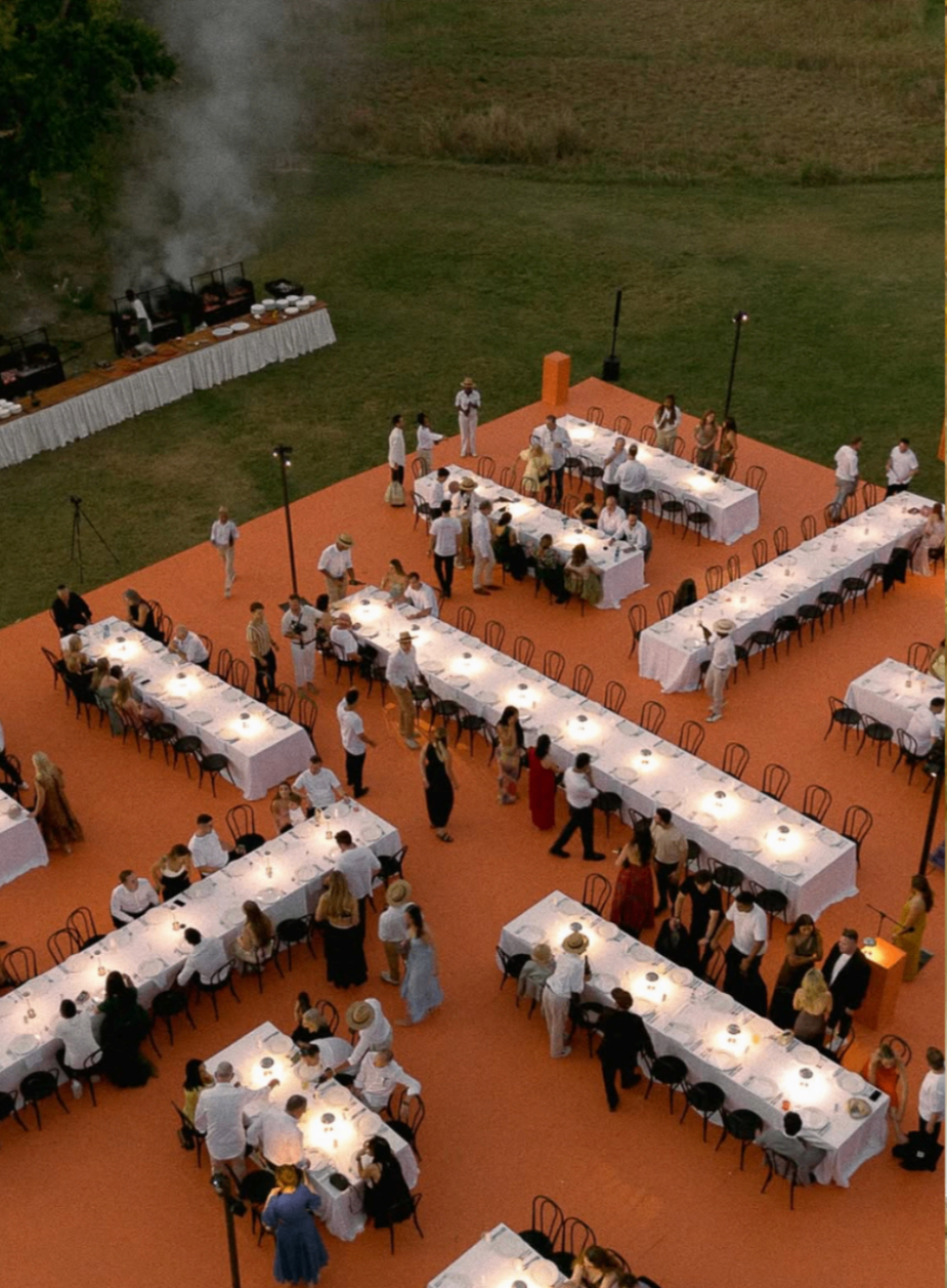 Overhead view of a long-table dinner laid out on bold terracotta flooring