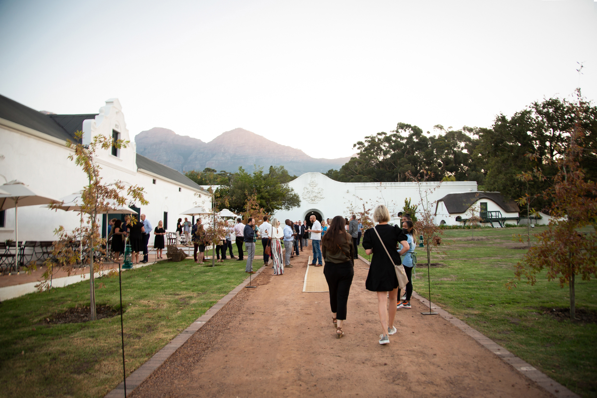 Guests mingling in the manor courtyard with mountain backdrop