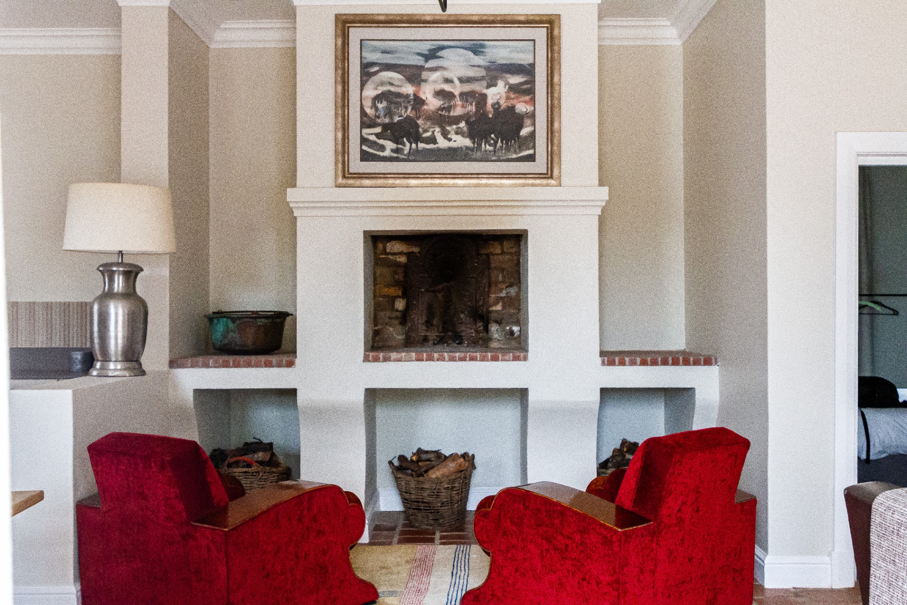 Merle Cottage lounge with fireplace and red velvet armchairs
