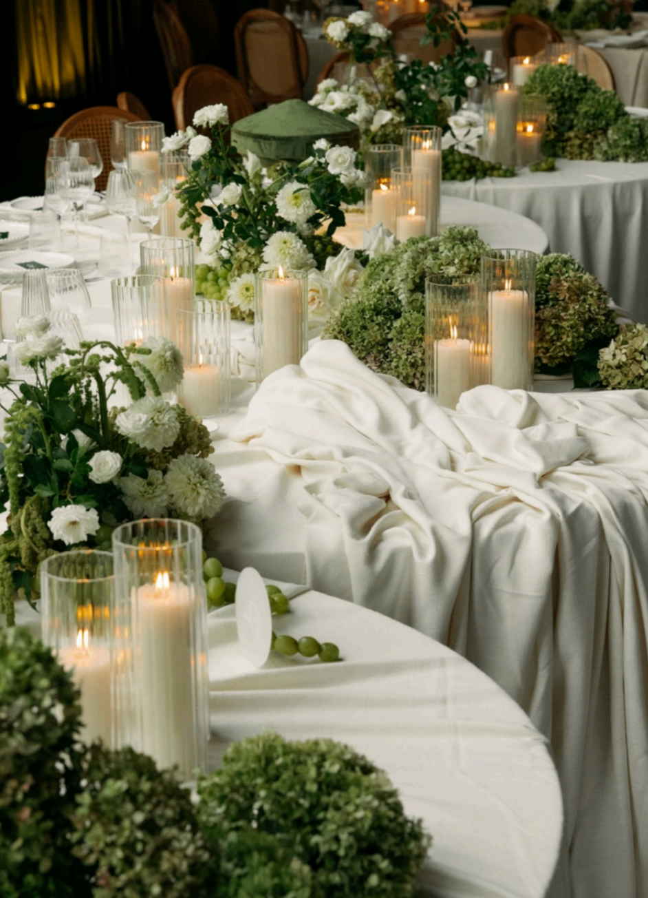 Candlelit reception table layered with white florals and soft draped linens